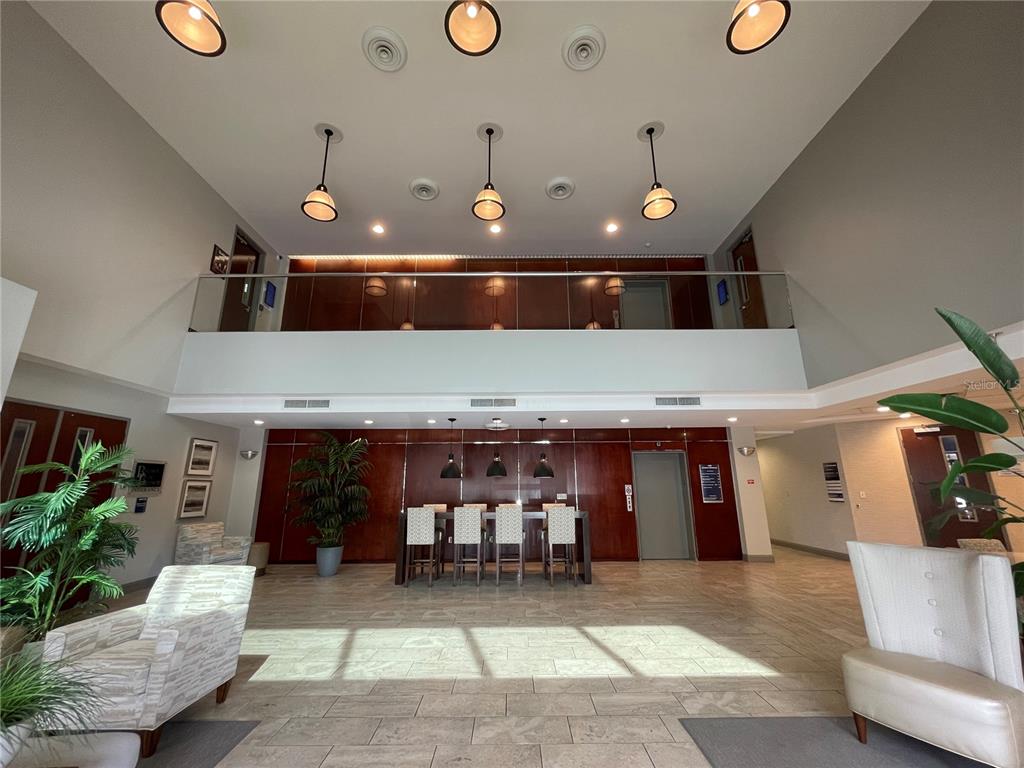 A modern lobby features a high ceiling, wood-paneled walls, a seating area, and pendant lighting — 1300 CITIZENS BOULEVARD, LEESBURG, FL