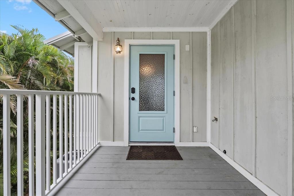 A light blue front door with textured glass sits on a covered wooden porch — 1306 MCGREGOR STREET, PUNTA GORDA, FL