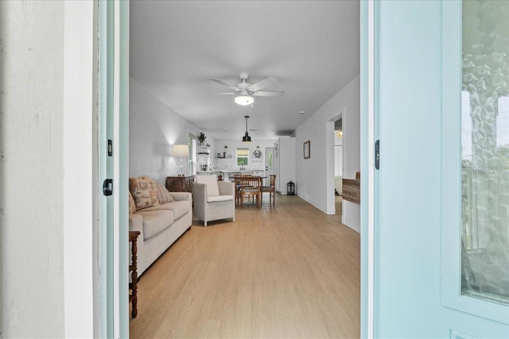 A view through an open doorway into an open-concept living area with light wood flooring — 1306 MCGREGOR STREET, PUNTA GORDA, FL