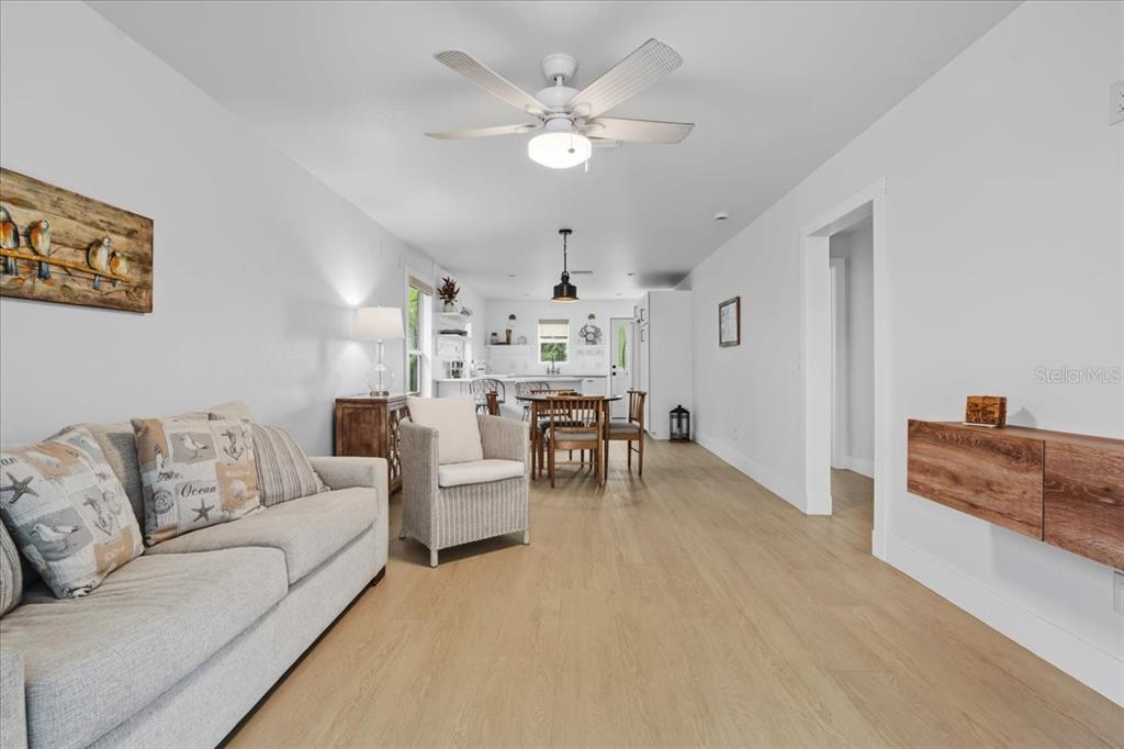 A living room with light wood flooring flows into a dining area and kitchen — 1306 MCGREGOR STREET, PUNTA GORDA, FL