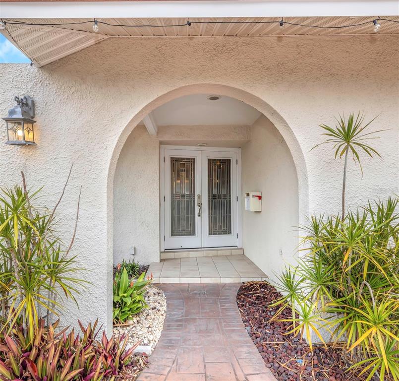 An arched entryway leads to double glass-paneled doors with a tiled porch and landscaping — 4313 50TH PLACE S, ST PETERSBURG, FL