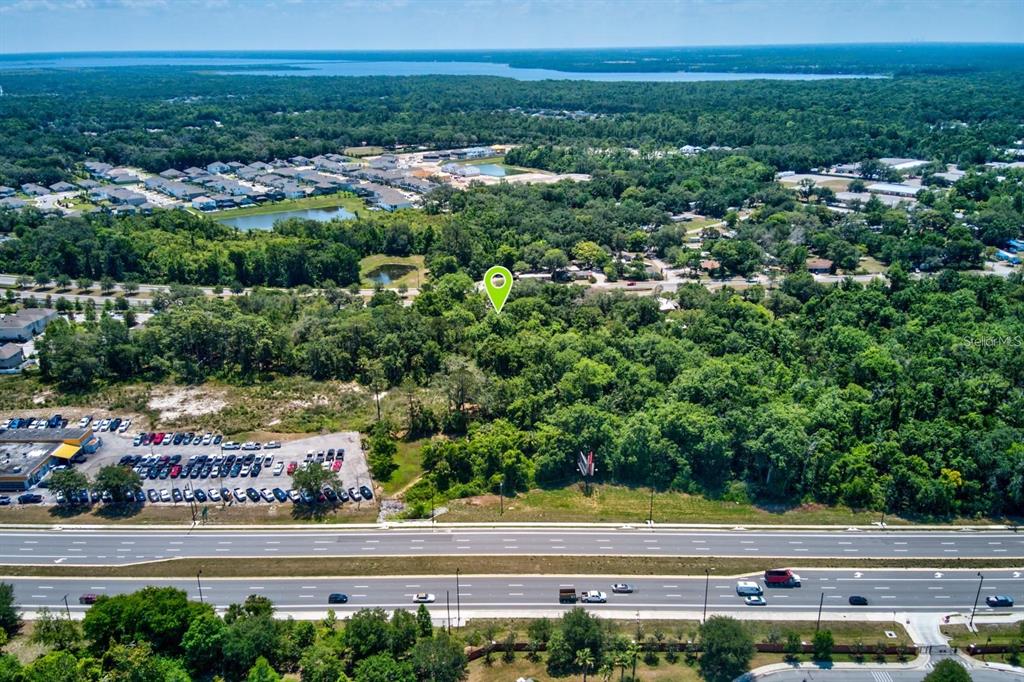 An aerial view shows a wooded lot marked by a green pin near a highway — 4750 N RONALD REAGAN BOULEVARD, SANFORD, FL