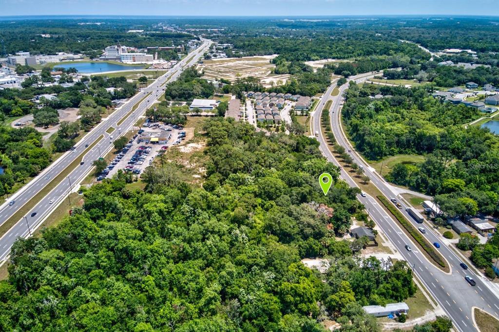 An aerial view shows a wooded lot marked with a pin between two multi-lane roads — 4750 N RONALD REAGAN BOULEVARD, SANFORD, FL