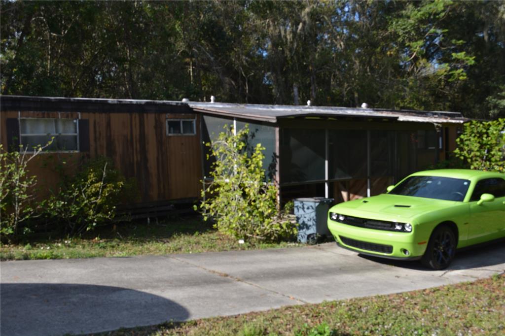 A single-story mobile home with a screened-in porch and a bright green car parked outside — 4750 N RONALD REAGAN BOULEVARD, SANFORD, FL