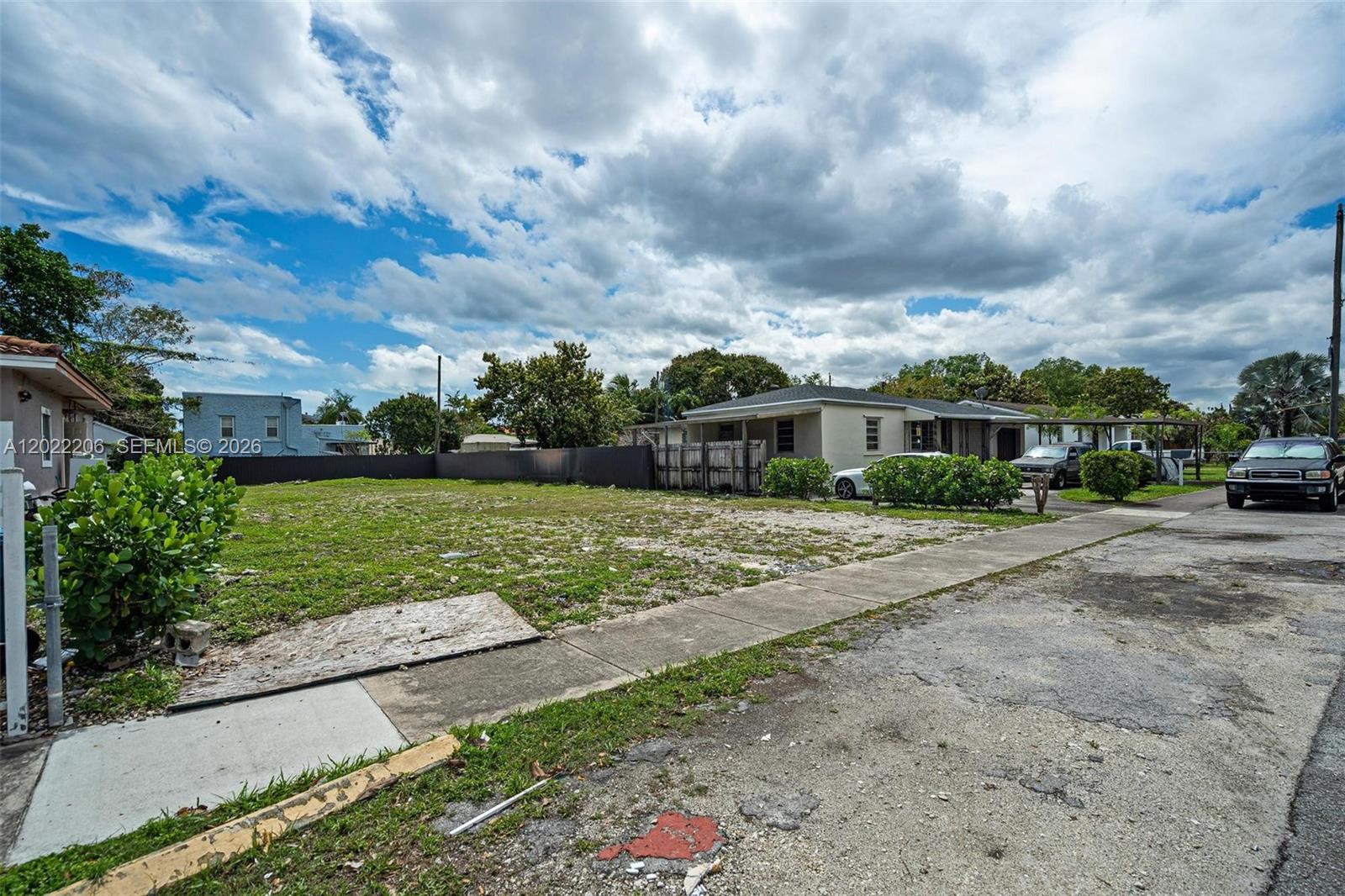 A vacant, grassy residential lot sits next to a single-story house with a driveway — 3056 SW 13th St, Miami FL 33145, MIAMI, FL