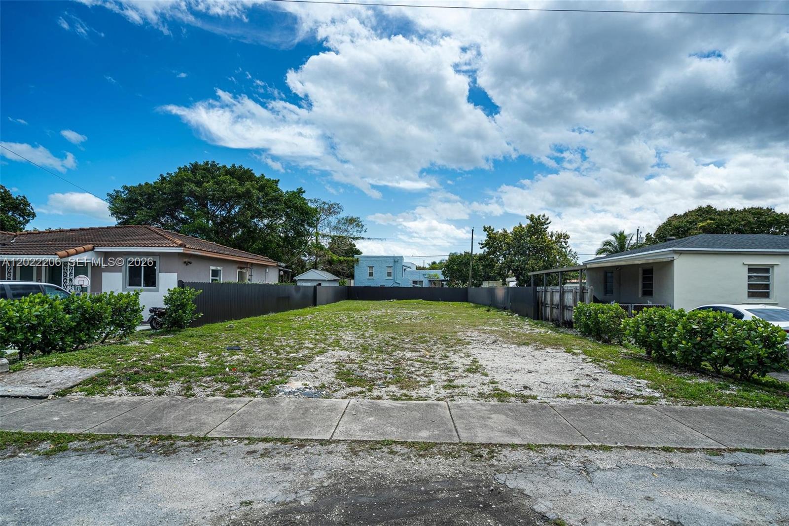 A vacant, rectangular residential lot is enclosed by a dark fence between two houses — 3056 SW 13th St, Miami FL 33145, MIAMI, FL