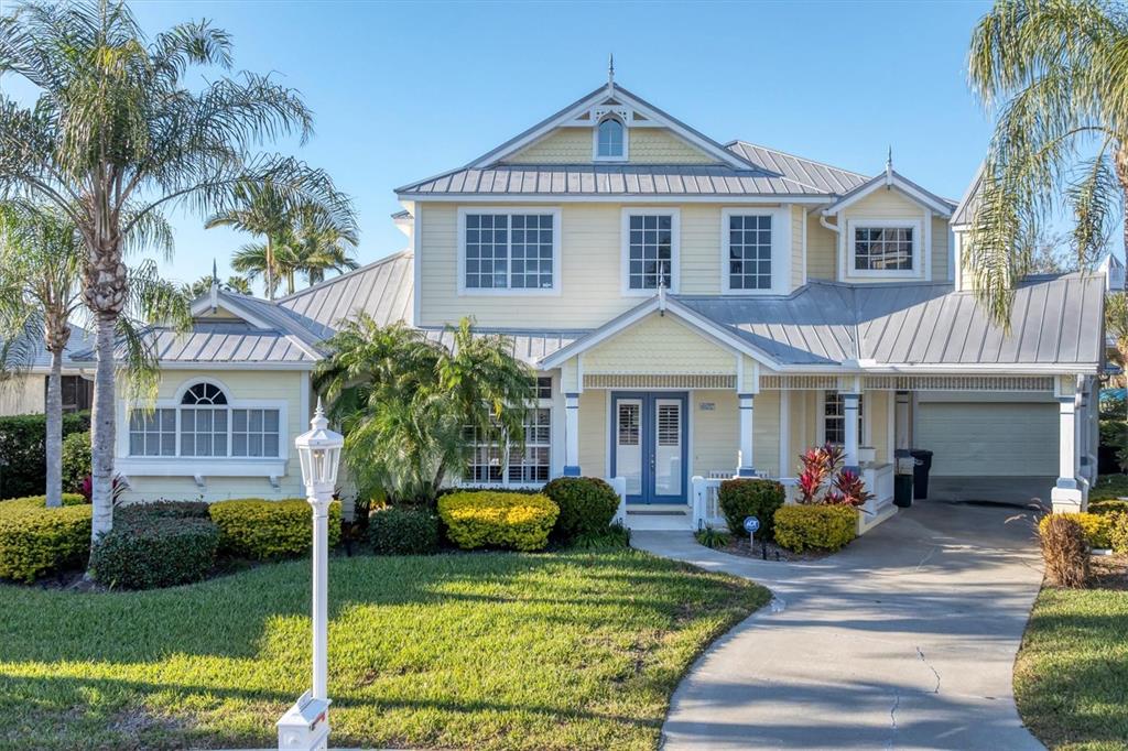 A two-story yellow house with a metal roof, front porch, and a concrete driveway — 4627 BARRACUDA DRIVE, BRADENTON, FL