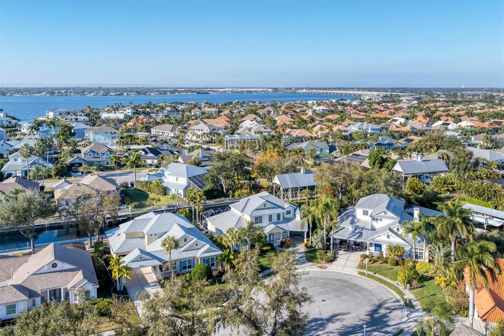 An aerial view of a residential neighborhood featuring houses with metal roofs near water — 4627 BARRACUDA DRIVE, BRADENTON, FL