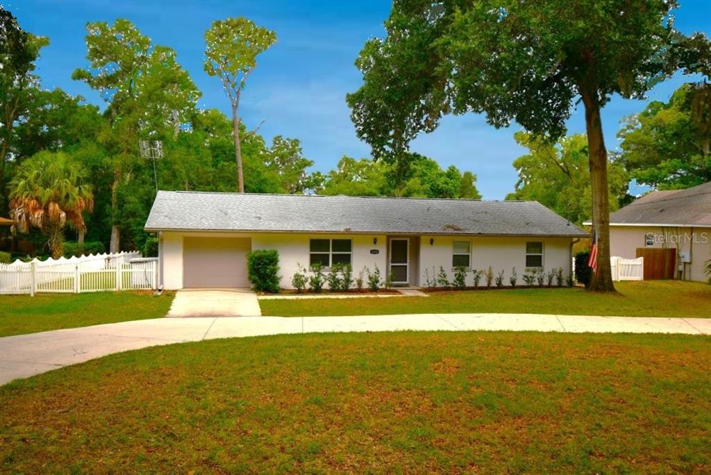 A single-story house with a white exterior, attached garage, and a curved concrete driveway — 2898 ALAMEDA DEL NORTE, EUSTIS, FL
