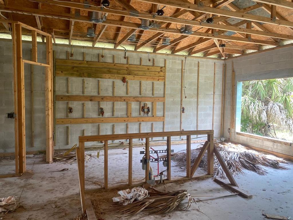 An unfinished room with exposed wood framing, concrete block walls, and a large window — 10035 HACKENSACK STREET, PORT CHARLOTTE, FL