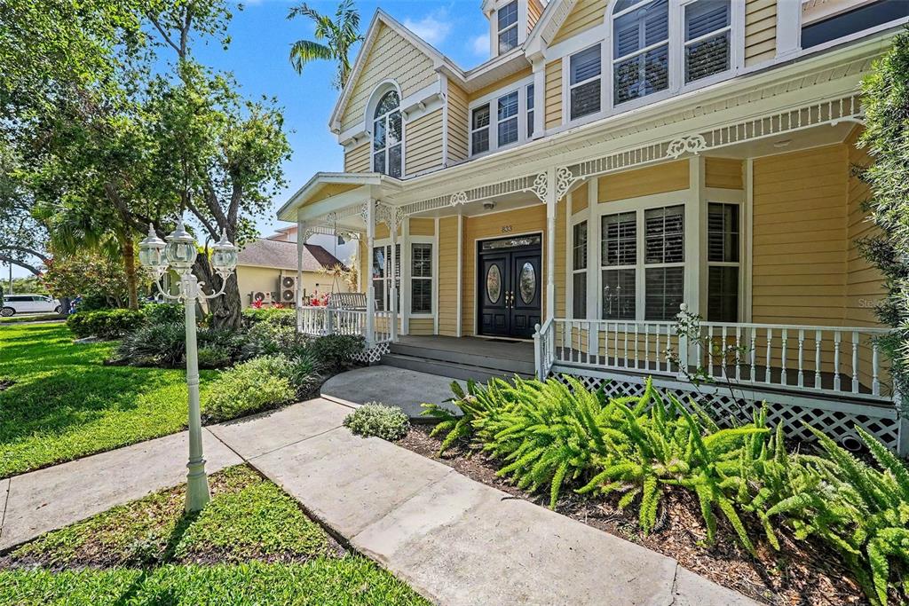 A yellow two-story house features a front porch, a concrete walkway, and a lamp post — 833 MARCO DRIVE NE, ST PETERSBURG, FL