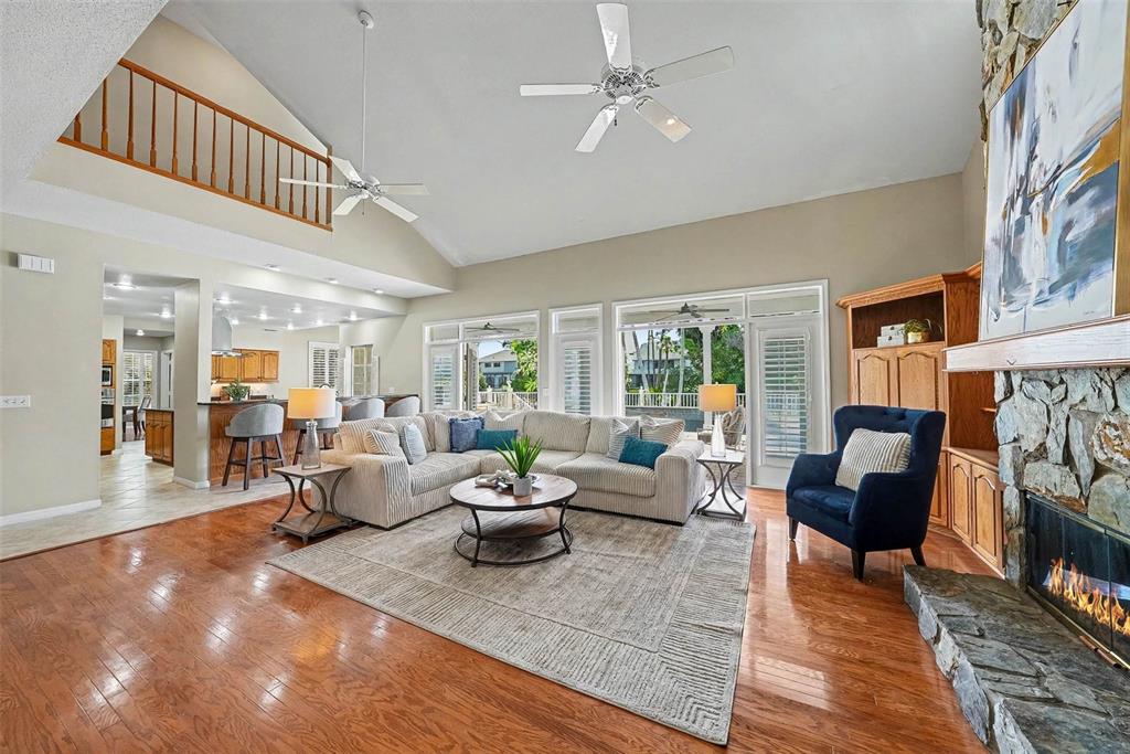 A spacious living room features hardwood floors, a stone fireplace, and a vaulted ceiling — 833 MARCO DRIVE NE, ST PETERSBURG, FL