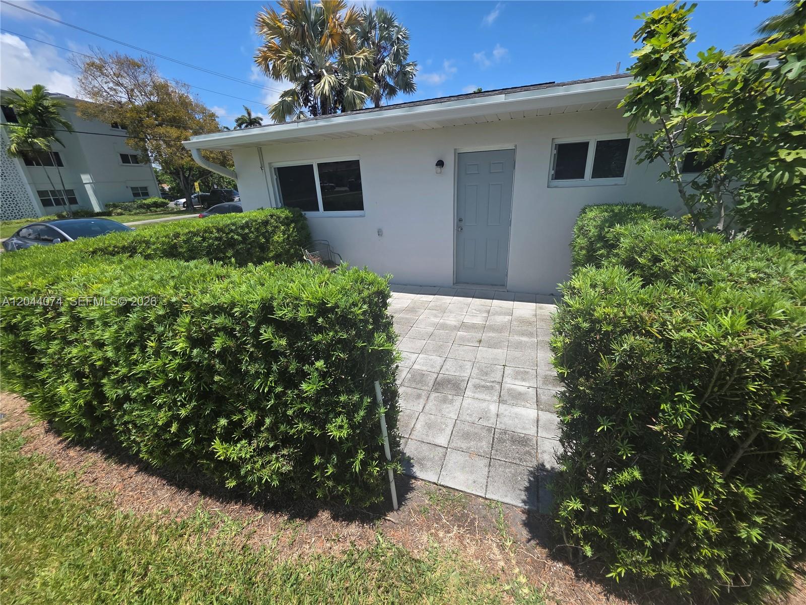 A paved patio sits in front of a white building exterior with a gray door — 120 NE 10th Ave # 3, Hallandale Beach FL 33009, HALLANDALE BEACH, FL