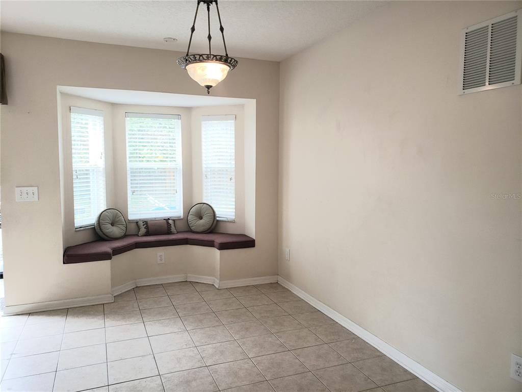 An empty living room features light-colored tile flooring, white walls, a ceiling fan, and stairs — 10310 LAKESIDE VISTA DRIVE, RIVERVIEW, FL