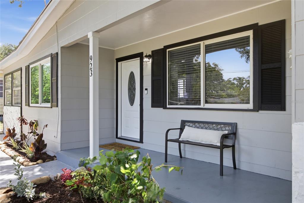 A gray house exterior features a front porch with a bench and a white door — 923 N PALM DRIVE SW, LARGO, FL