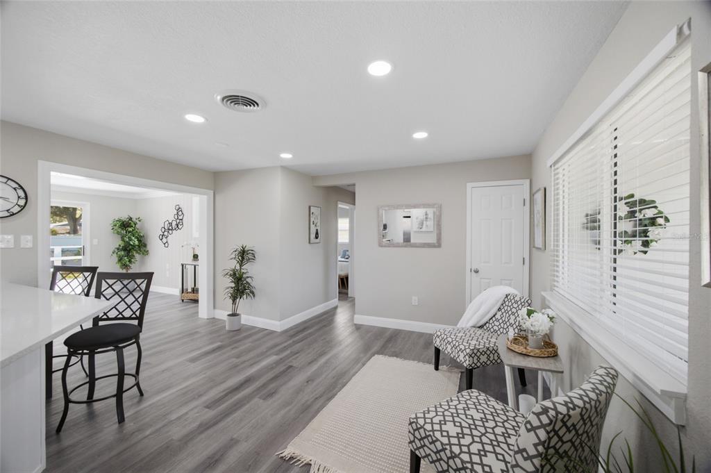 A bright room with gray wood-look flooring, recessed lighting, and a small seating area — 923 N PALM DRIVE SW, LARGO, FL