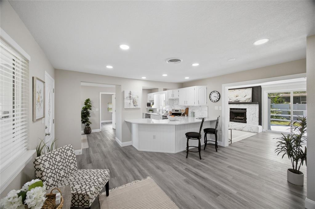 An open-concept kitchen with white cabinets and a breakfast bar overlooks a living area — 923 N PALM DRIVE SW, LARGO, FL