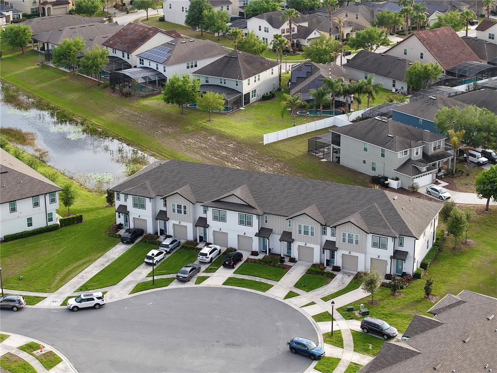 An aerial view shows a multi-unit townhouse building with driveways facing a cul-de-sac — 1542 DISCOVERY STREET, DAVENPORT, FL