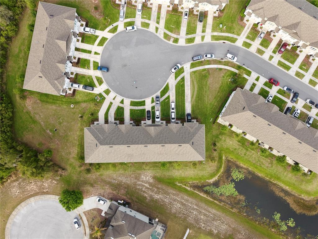 An aerial view shows a residential cul-de-sac with townhomes, driveways, and a small pond — 1542 DISCOVERY STREET, DAVENPORT, FL