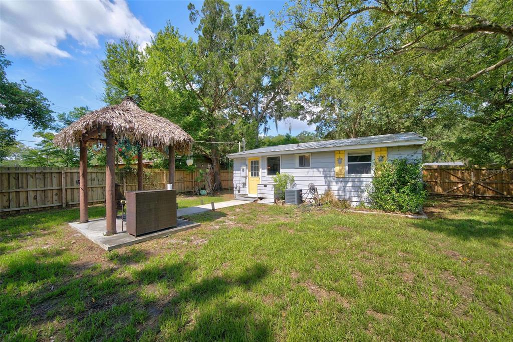 A small, light-gray house with a yellow door and a thatched-roof tiki bar outside — 2317 S SUMMERLIN AVENUE, SANFORD, FL