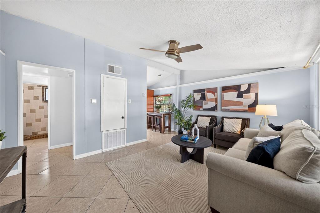 A living room with light blue walls, tile flooring, a ceiling fan, and neutral furniture — 2317 S SUMMERLIN AVENUE, SANFORD, FL