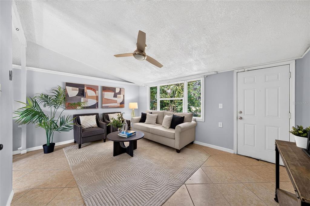A living room features light gray walls, tile flooring, a beige sofa, and a ceiling fan — 2317 S SUMMERLIN AVENUE, SANFORD, FL