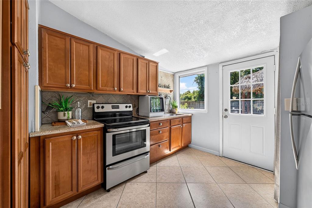 A kitchen features wood cabinets, stainless steel appliances, tile flooring, and a glass-paneled exterior door — 2317 S SUMMERLIN AVENUE, SANFORD, FL