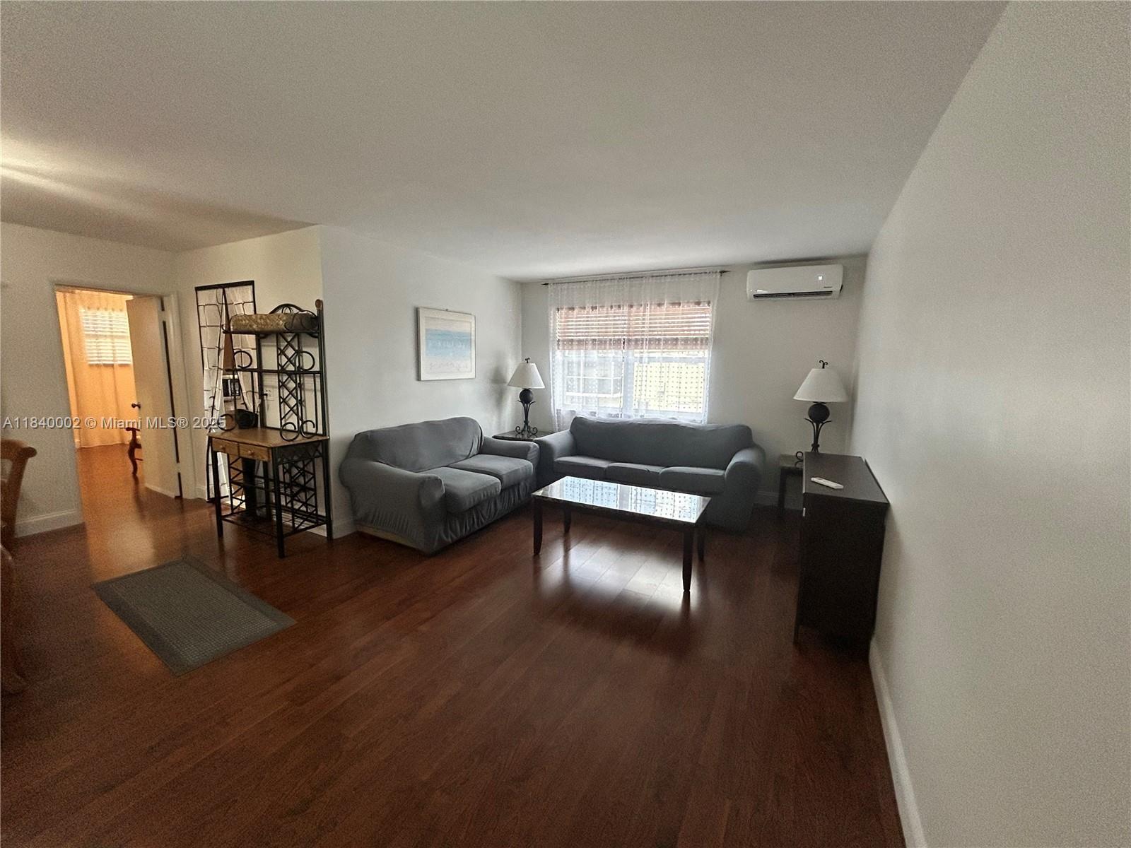 A living room features hardwood floors, two gray sofas, a coffee table, and a window — 1717 Rodman St # 15, Hollywood FL 33020, HOLLYWOOD, FL