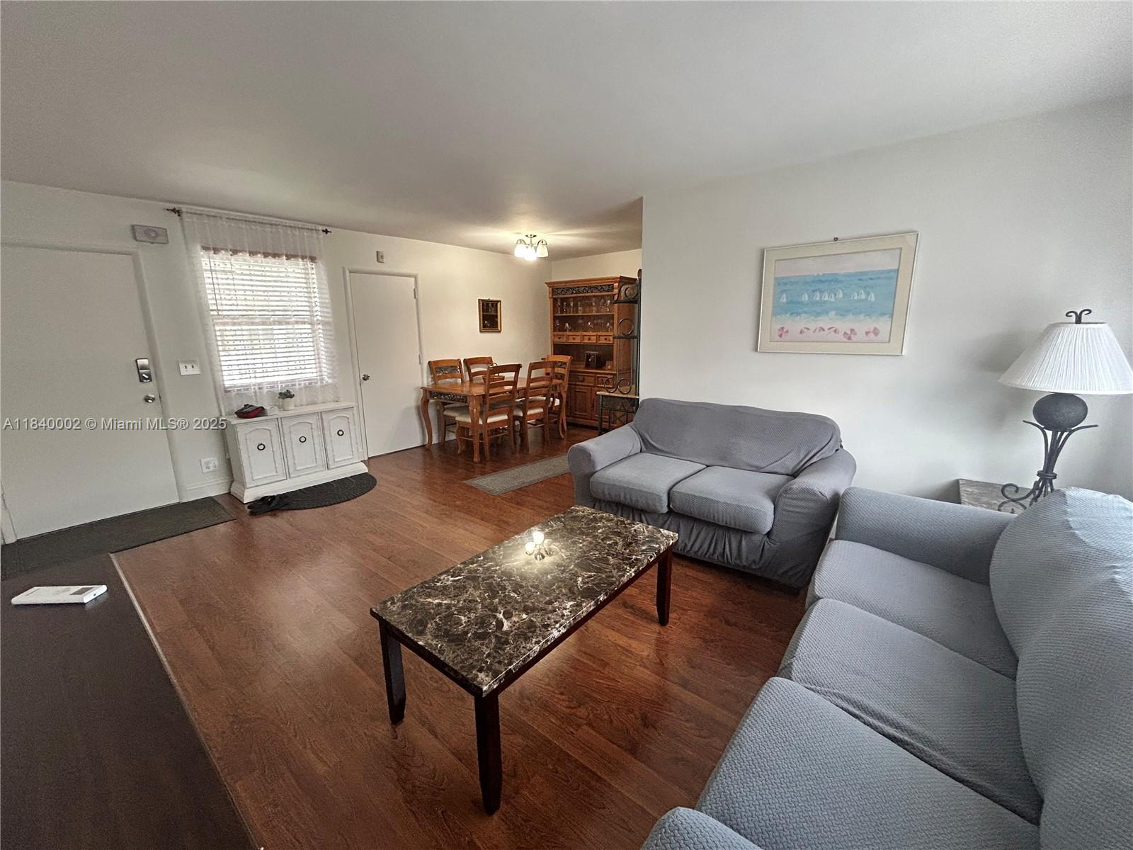 A living and dining room area features wood flooring, light blue sofas, and a hutch — 1717 Rodman St # 15, Hollywood FL 33020, HOLLYWOOD, FL