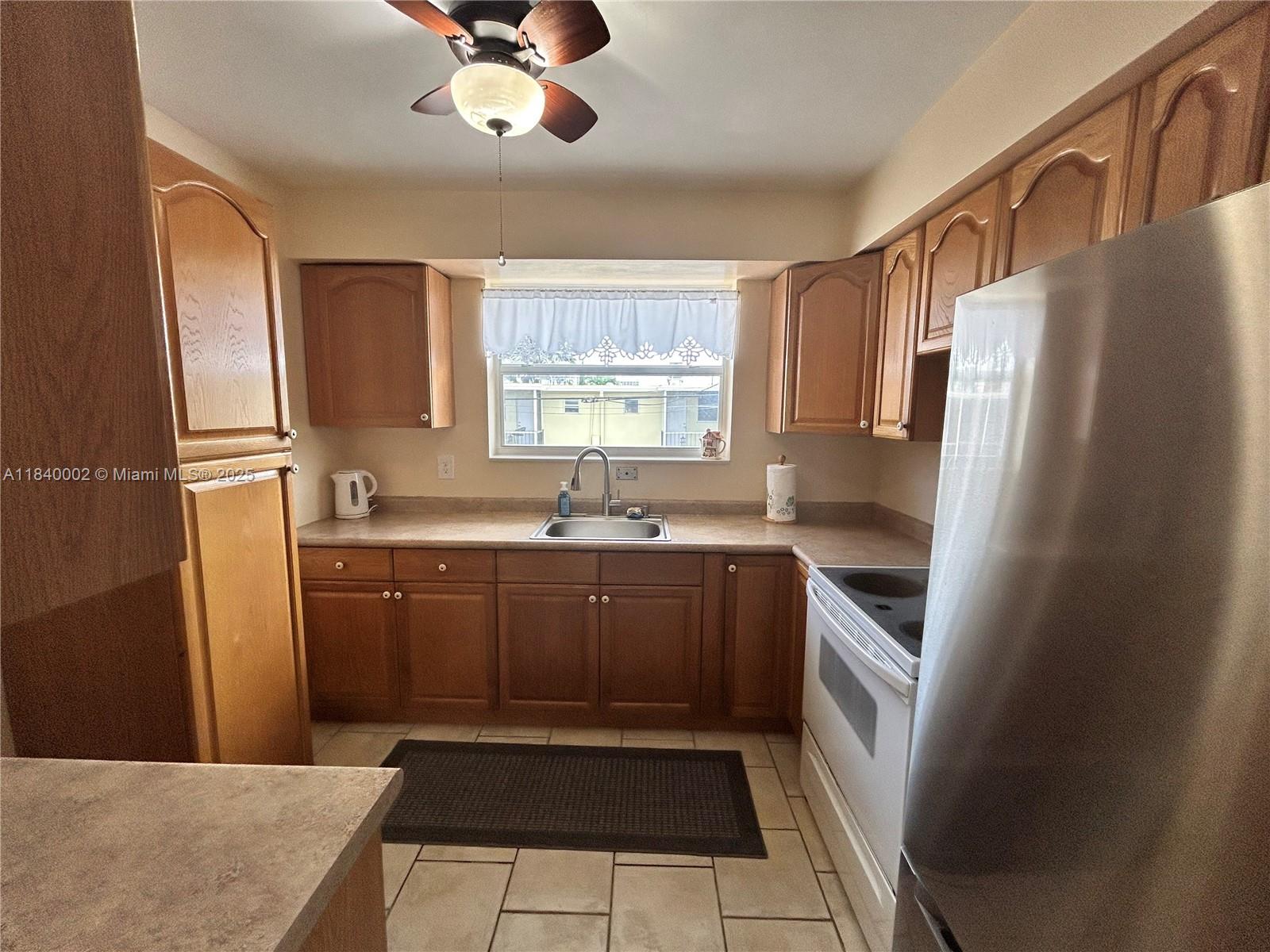 A kitchen features wooden cabinets, stainless steel appliances, a sink, and a ceiling fan — 1717 Rodman St # 15, Hollywood FL 33020, HOLLYWOOD, FL