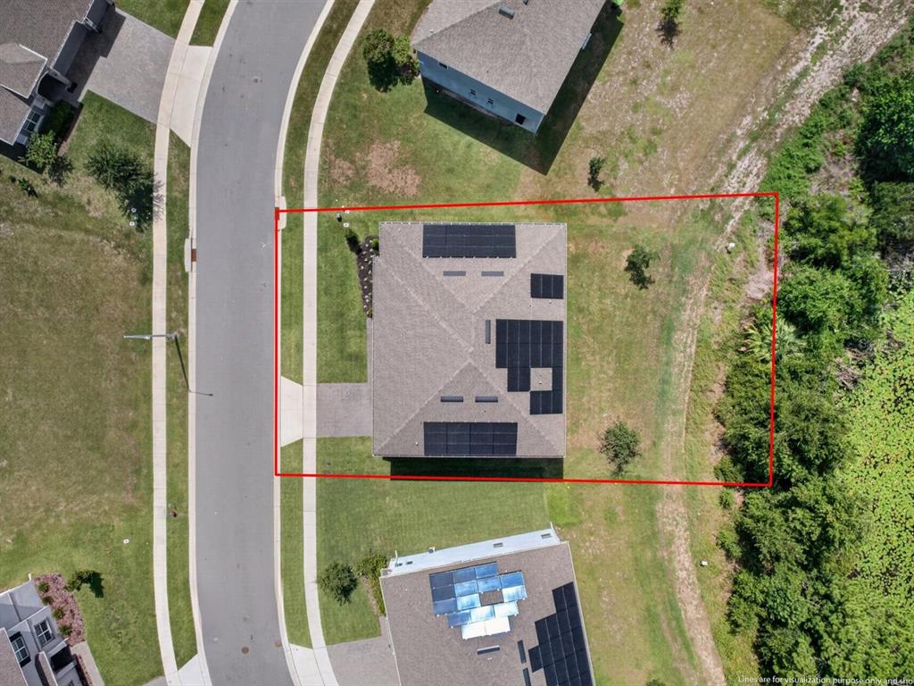 An aerial view shows a house with solar panels on its roof within a residential neighborhood — 603 AVILA PLACE, HOWEY IN THE HILLS, FL