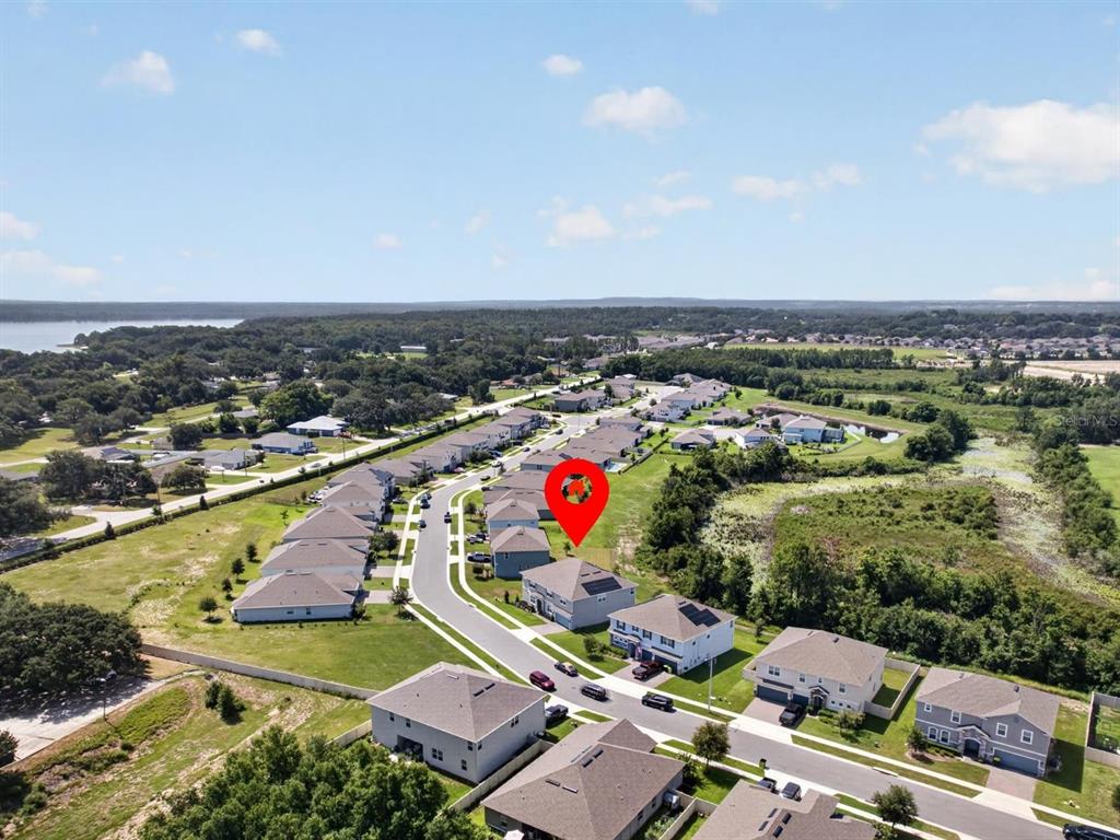 An aerial view shows a residential neighborhood with a red location pin over a house — 603 AVILA PLACE, HOWEY IN THE HILLS, FL