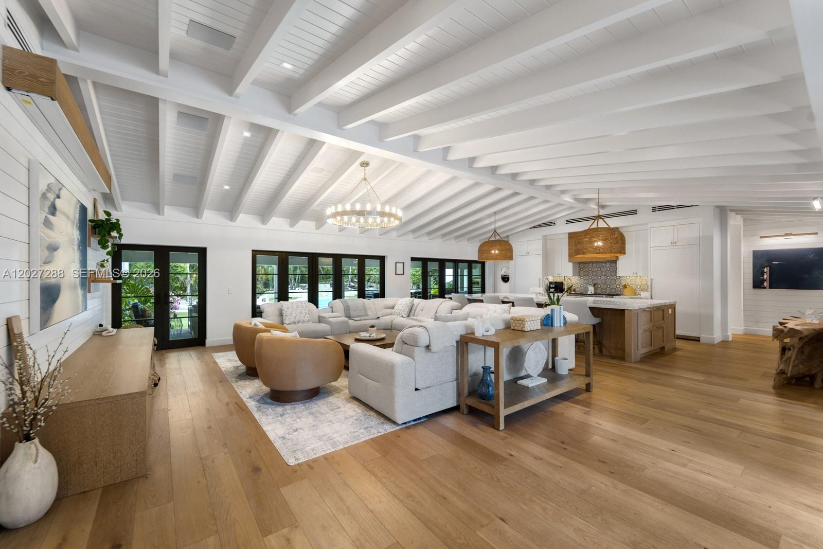 A spacious open-concept living room features a vaulted beamed ceiling, hardwood floors, and a kitchen — 7101 SW 66th St, Miami FL 33143, MIAMI, FL
