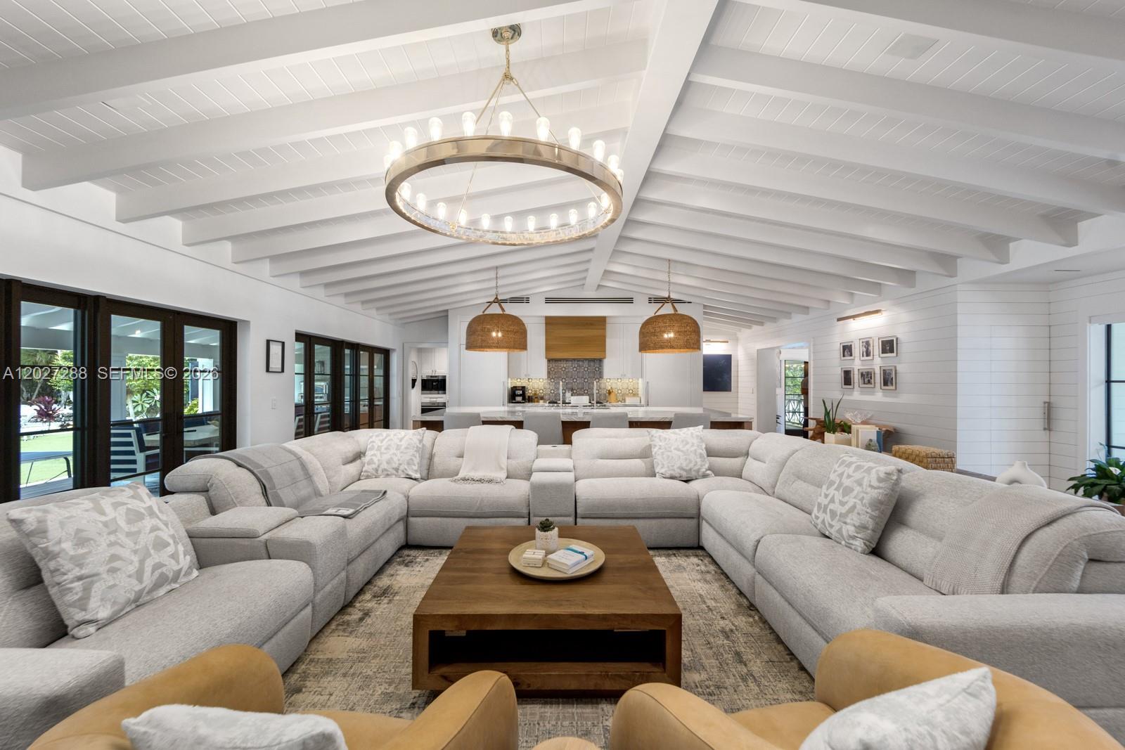 A spacious living room features a large sectional sofa, wooden coffee table, and vaulted ceilings — 7101 SW 66th St, Miami FL 33143, MIAMI, FL