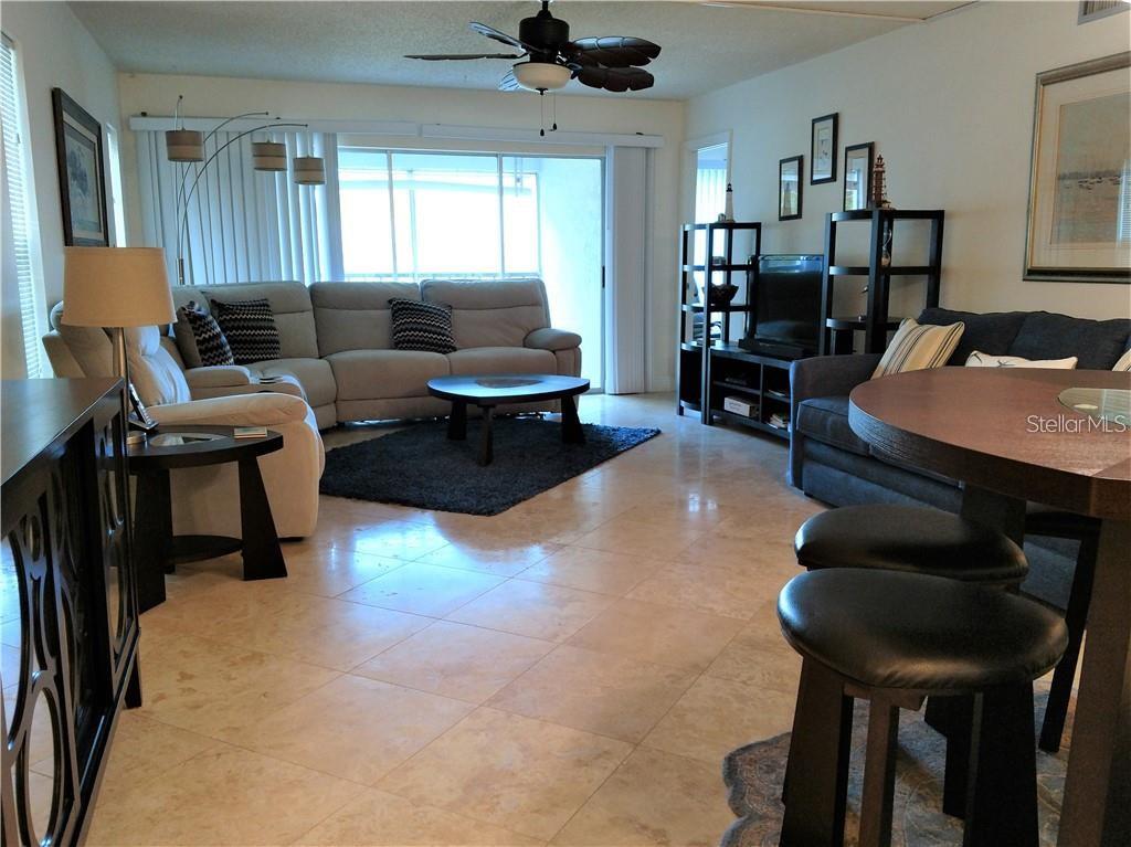 A living room features light tile floors, a sectional sofa, and a dining table — 8703 BARDMOOR BOULEVARD UNIT 201, SEMINOLE, FL