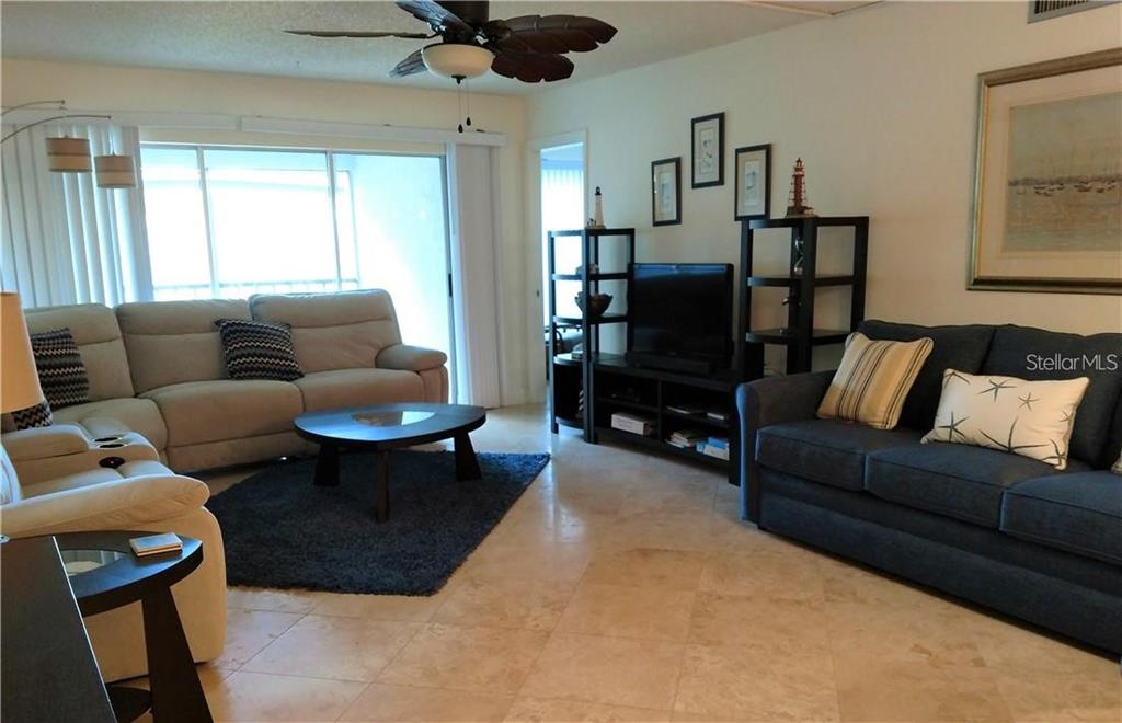 A living room features a beige sectional, a blue sofa, tile floors, and a ceiling fan — 8703 BARDMOOR BOULEVARD UNIT 201, SEMINOLE, FL