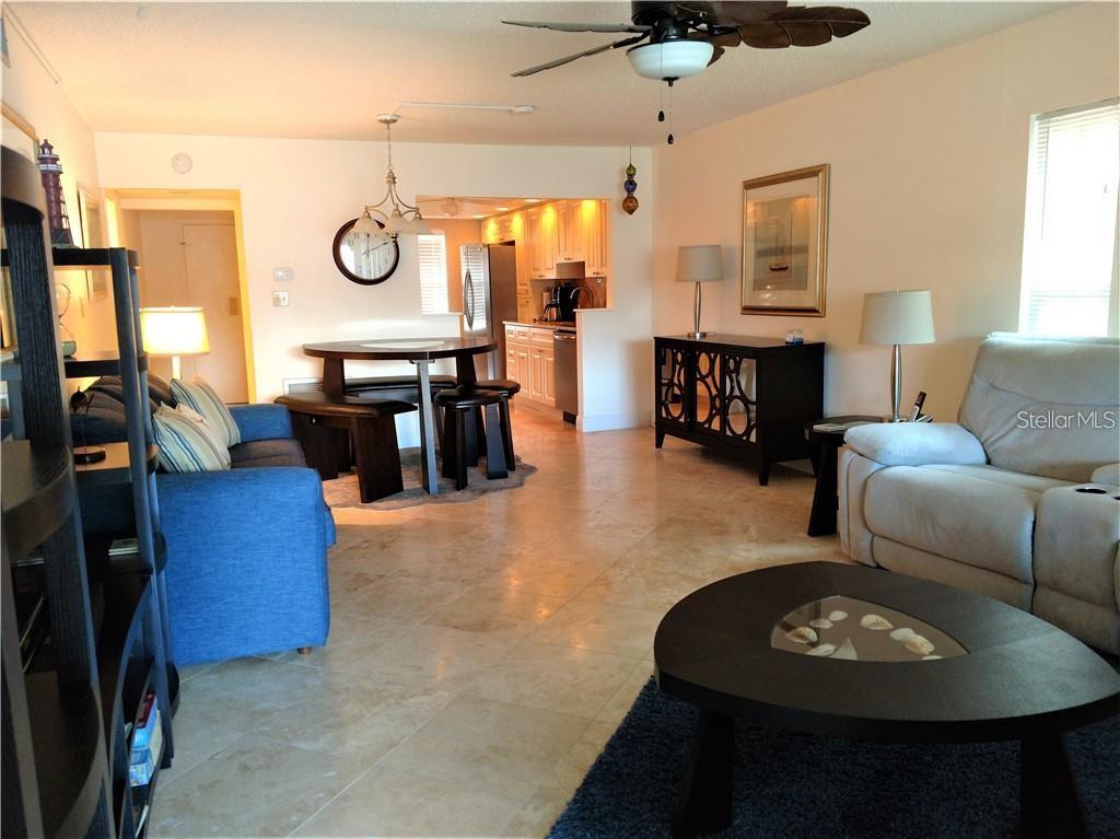 A living room and dining area with tile floors, a blue sofa, and white furniture — 8703 BARDMOOR BOULEVARD UNIT 201, SEMINOLE, FL