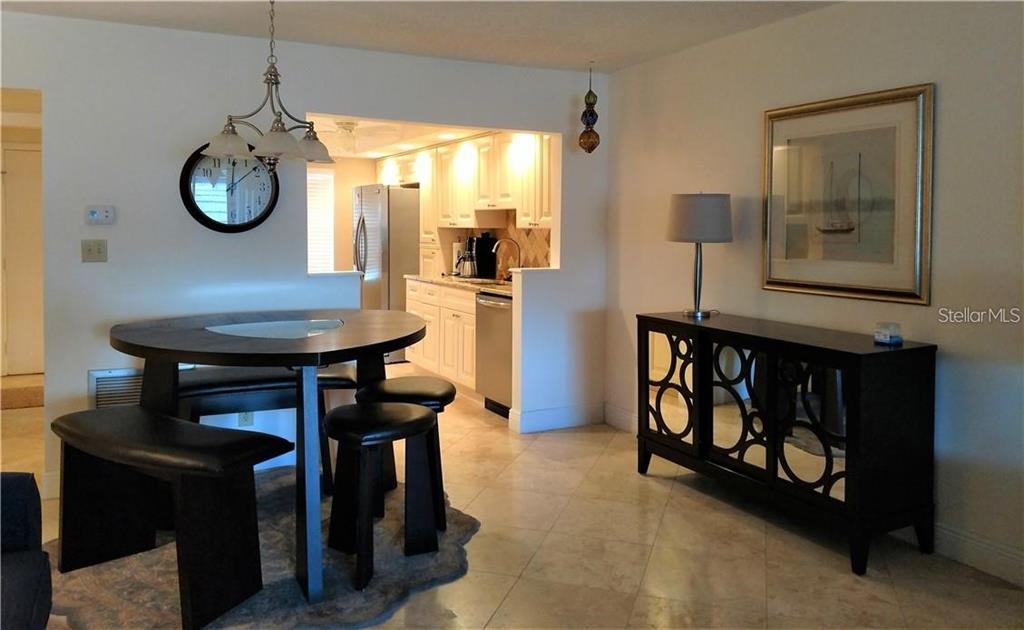 A dining area with a round table and chairs opens into a kitchen with white cabinets — 8703 BARDMOOR BOULEVARD UNIT 201, SEMINOLE, FL