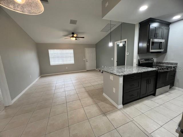 An open-concept kitchen with dark cabinets and a granite island overlooks a tiled living area — 11969 XAVIER AVENUE, PORT CHARLOTTE, FL