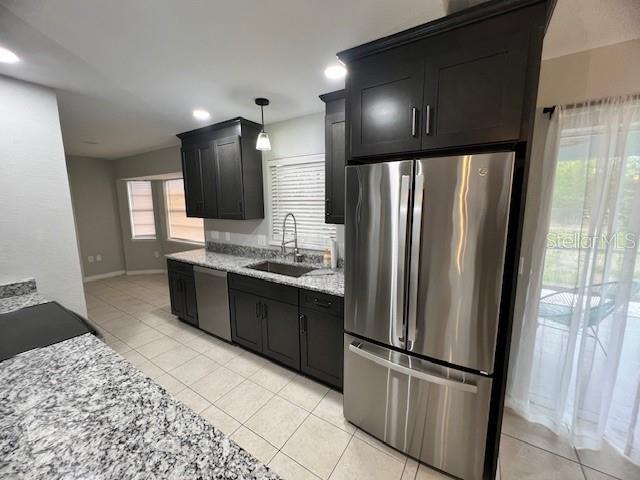 A kitchen features dark cabinetry, granite countertops, stainless steel appliances, and light-colored tile flooring — 11969 XAVIER AVENUE, PORT CHARLOTTE, FL
