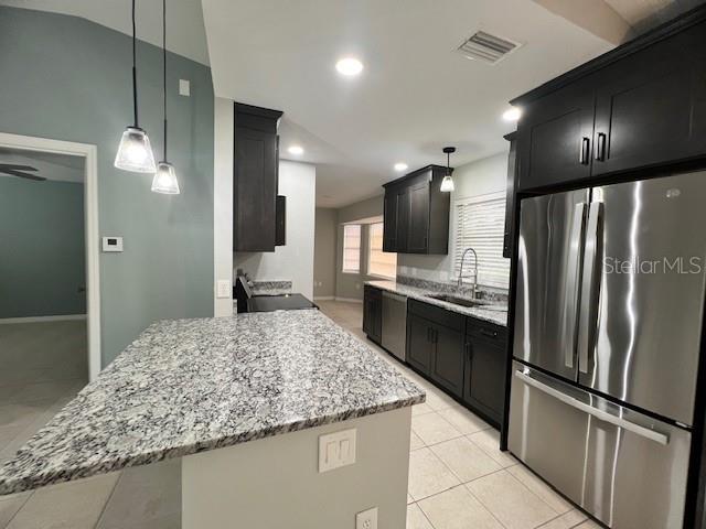 A kitchen features dark cabinets, granite countertops, a stainless steel refrigerator, and two pendant lights — 11969 XAVIER AVENUE, PORT CHARLOTTE, FL