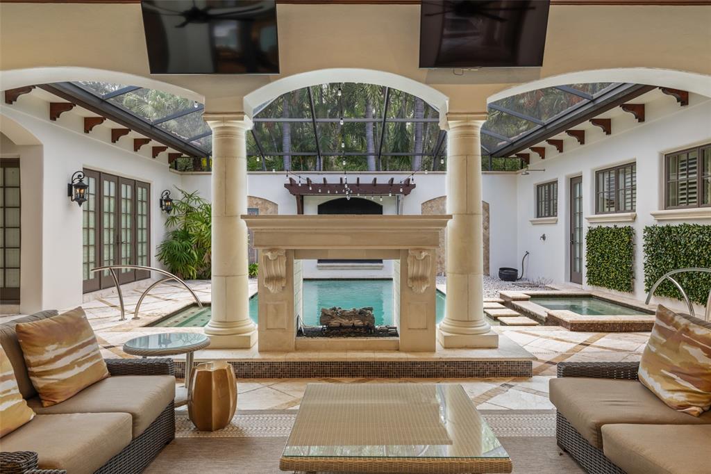 A covered outdoor living area features a stone fireplace, seating, and a pool view — 4812 ALEXANDRA GARDEN COURT, WINDERMERE, FL