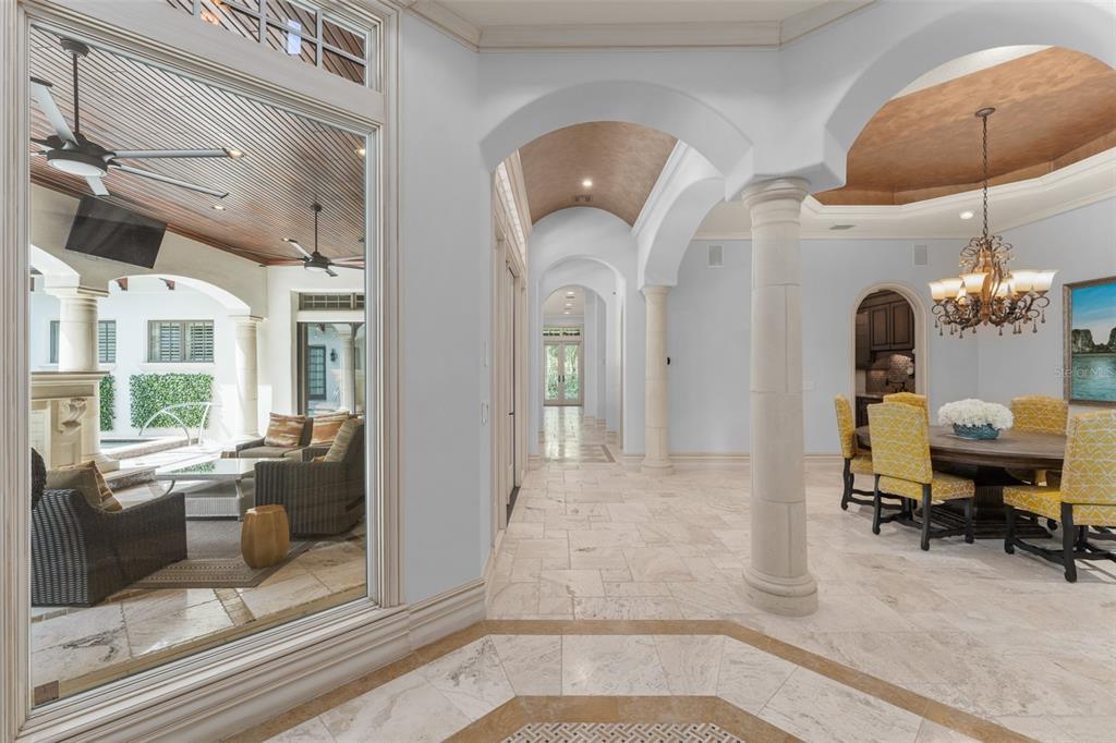 A dining room with yellow chairs and arched hallways connects to a covered outdoor patio — 4812 ALEXANDRA GARDEN COURT, WINDERMERE, FL