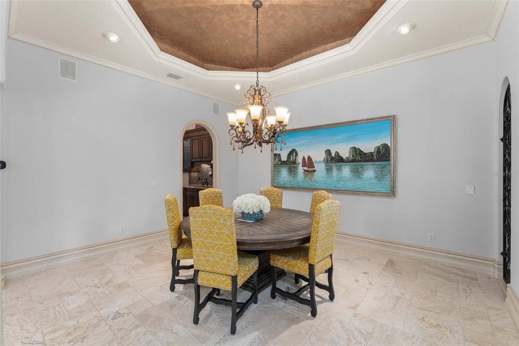 A dining room features a round wooden table, yellow patterned chairs, and a tray ceiling — 4812 ALEXANDRA GARDEN COURT, WINDERMERE, FL