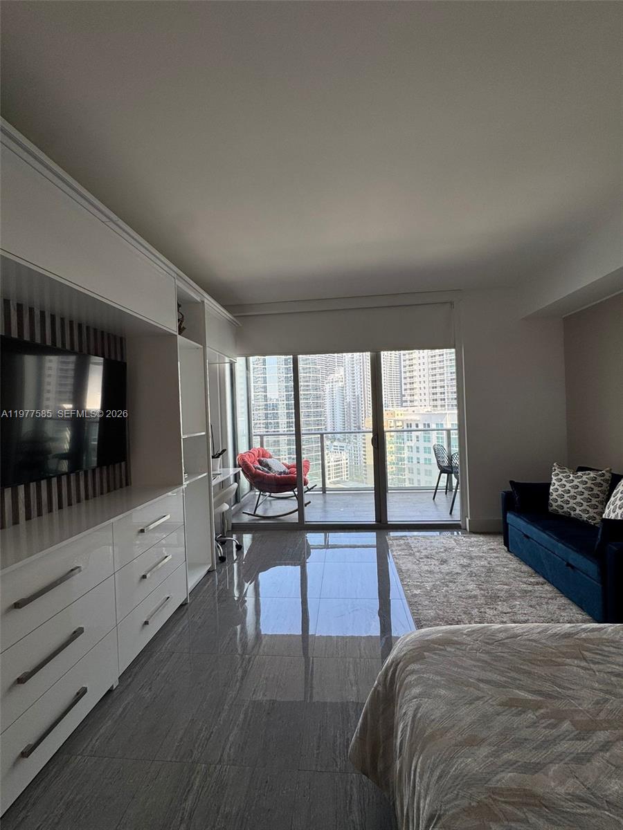 A bedroom features glossy tile floors, a built-in media unit, and a balcony with city views — 1300 Brickell Bay Dr # 2512, Miami FL 33131, MIAMI, FL