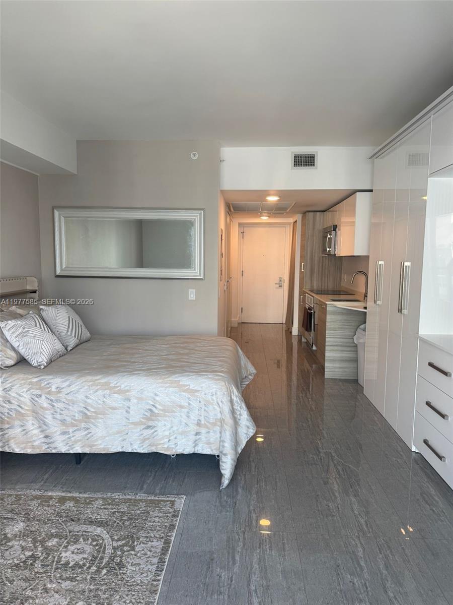 A studio apartment features a bed, a kitchenette, and glossy white storage cabinets — 1300 Brickell Bay Dr # 2512, Miami FL 33131, MIAMI, FL