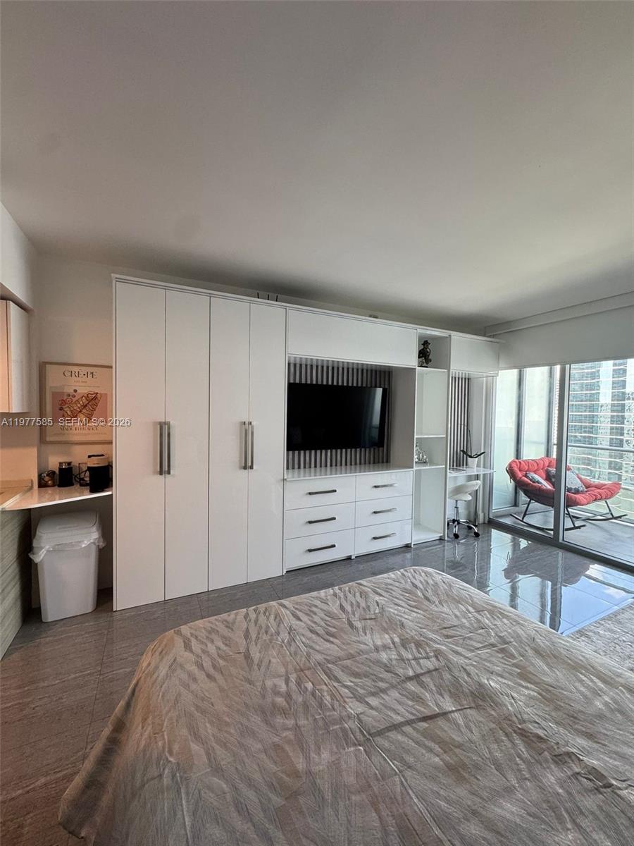 A bedroom features a large white built-in storage unit, a television, and a balcony view — 1300 Brickell Bay Dr # 2512, Miami FL 33131, MIAMI, FL