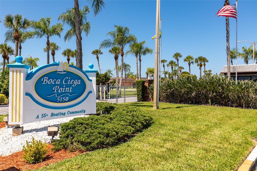 A sign for a 55+ boating community stands in a landscaped area with palm trees — 1 BOCA CIEGA POINT BOULEVARD UNIT 206, ST PETERSBURG, FL