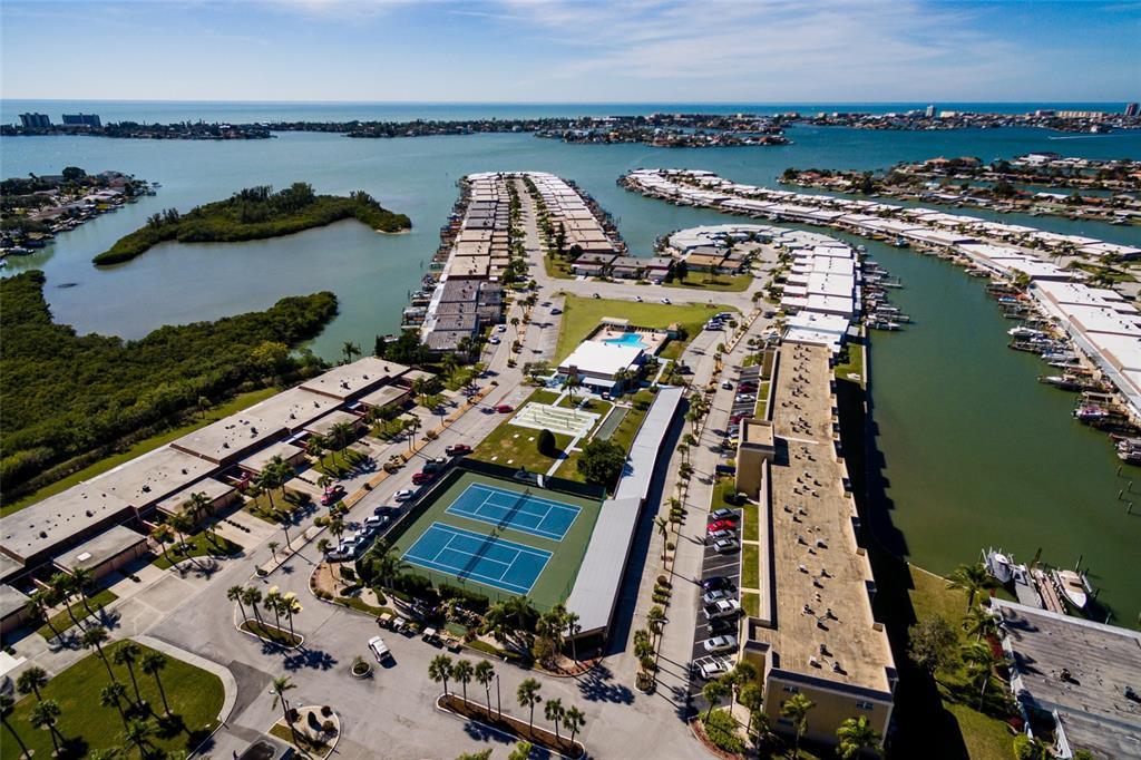 An aerial view shows a waterfront residential complex with tennis courts and boat slips — 1 BOCA CIEGA POINT BOULEVARD UNIT 206, ST PETERSBURG, FL