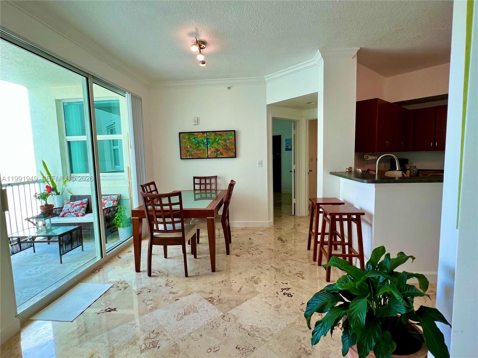 A dining area with a glass-top table, tile floors, and an adjacent balcony — 9172 Collins Ave # 305, Surfside FL 33154, SURFSIDE, FL